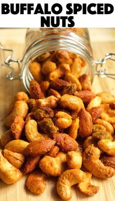 a jar full of buffalo spiced nuts on top of a wooden table with text overlay