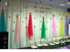 there are many chairs in front of the colorful curtain with stars and ribbons on it