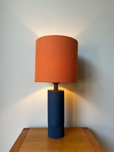 a lamp that is sitting on top of a wooden table next to a white wall