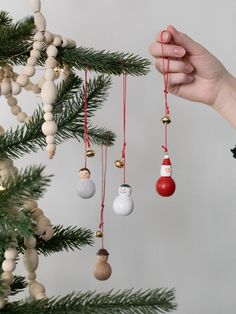 someone is holding ornaments in their hand and hanging them from the christmas tree with other ornaments