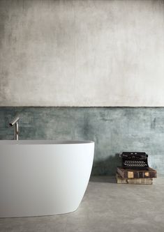 a white bath tub sitting next to a wooden box with an old typewriter on it