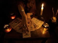 a person sitting at a table with cards and candles