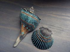 two seashells on a wooden surface with one shell painted in blue and orange