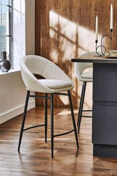 two white chairs sitting next to each other on top of a wooden floor in front of a window