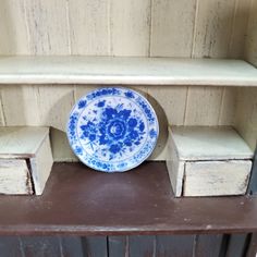 a blue and white plate sitting on top of a wooden shelf next to a wall