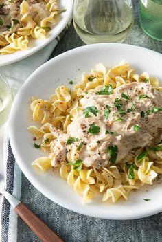 a white plate topped with pasta covered in sauce and garnished with parsley