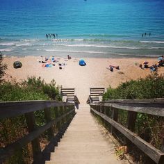 stairs lead down to the beach where people are relaxing