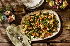 a white plate topped with asparagus and tofu next to a glass of wine