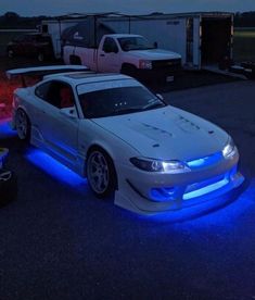 a white car with blue lights on it's hood parked in a parking lot