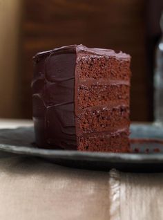 a piece of chocolate cake sitting on top of a plate next to a glass bottle