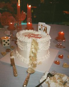 a white cake sitting on top of a table next to candles and other decor items