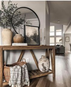 a wooden shelf with vases on top of it next to a mirror and other items