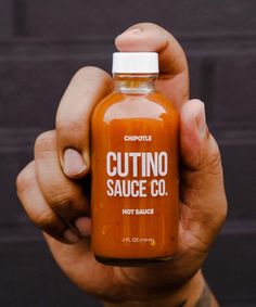 a person holding a bottle of hot sauce