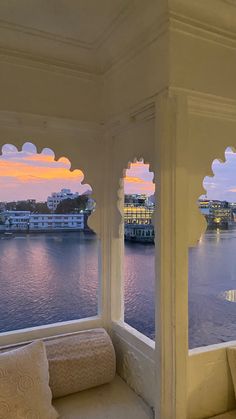 a room with two windows that look out onto the water and buildings in the distance