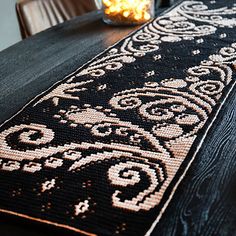 a table with a black and white rug on it next to a lit candle in a glass vase