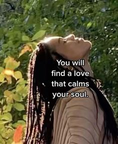 a woman with dreadlocks looking up at the sky and trees in the background