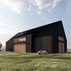 a large black barn sitting on top of a lush green field