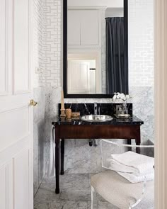 a bathroom sink sitting under a large mirror next to a white chair and counter top