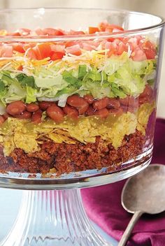 a layered salad with lettuce, tomatoes and other toppings in a glass dish