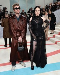 a man and woman standing next to each other in front of photographers at an event