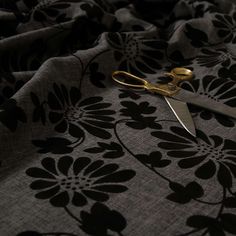 a pair of gold scissors sitting on top of a black and white flowered fabric