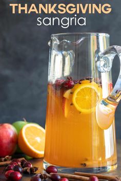 a pitcher filled with oranges and cranberries next to an apple cider