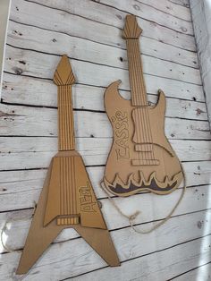 two wooden guitars sitting on top of a white wood floor next to each other with strings attached