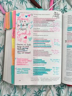 an open bible with writing on it and colored pencils in the pages next to it