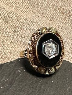 an antique diamond and black onyxite ring sitting on top of a stone slab