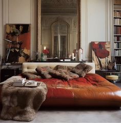 a bedroom with a large mirror, leather bed and bookshelf in the corner