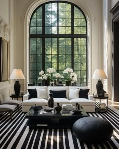 a living room with black and white striped carpeting, large windows, two lamps on either side of the couch