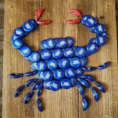 a blue crab made out of beer bottle caps sitting on top of a wooden table