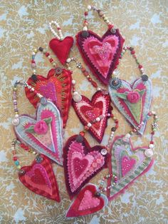 several heart shaped ornaments are arranged on a tablecloth with beaded necklaces and beads