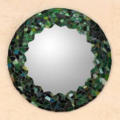 a round mirror with green and blue mosaic tiles on it