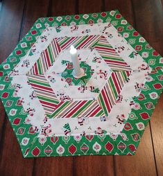 a candle sits on top of a green and white quilted christmas table runner with red, green, and white stripes