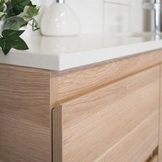 a white vase sitting on top of a wooden counter next to a sink and faucet