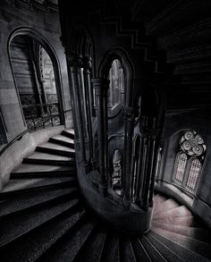 a spiral staircase in an old building with arched windows