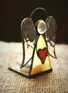 a stained glass angel with a heart on it's chest sitting on a table