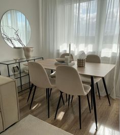 a dining room table with chairs and a round mirror