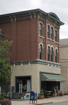 an old brick building on the corner of a street in front of a blue chair