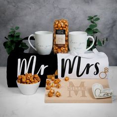 two mugs and some snacks are sitting on a table next to the couple's initials