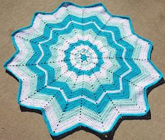 a blue and white crocheted doily on the ground