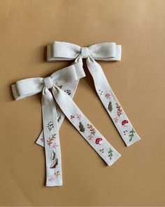 three white ribbons tied to each other on top of a brown surface with leaves and mushrooms