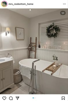 a white bath tub sitting inside of a bathroom next to a sink and window with shutters