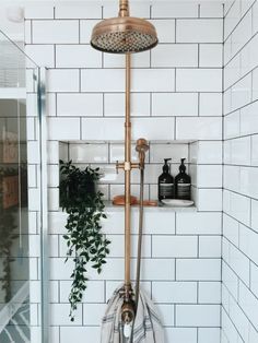 the shower head is mounted to the wall in this bathroom with white tiles and gold fixtures