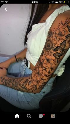 a woman is sitting in a chair with flowers on her arm and the other arm behind her