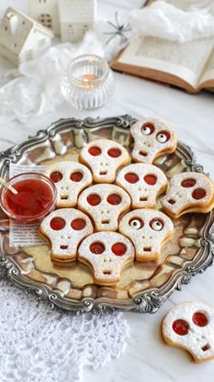 cookies decorated with sugar skulls and jelly eyes are on a plate next to an open book