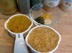 two bowls filled with rice and spices on a wooden table next to jars full of seasonings