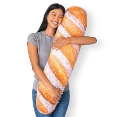 a woman is holding a large baguette in her hands and smiling at the camera