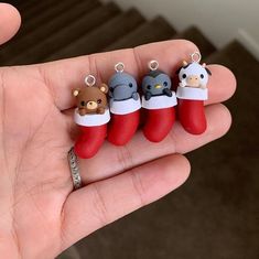 a person is holding four small charms in their hand, one has a monkey and two are wearing santa's stockings